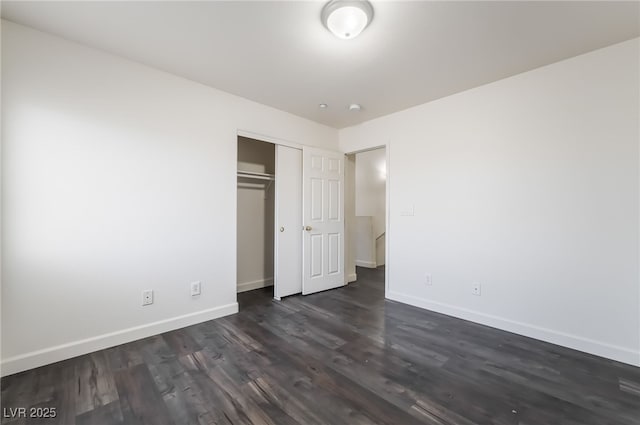 unfurnished bedroom with baseboards, dark wood-style flooring, and a closet