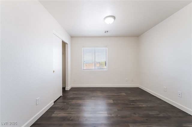 empty room featuring baseboards and dark wood finished floors