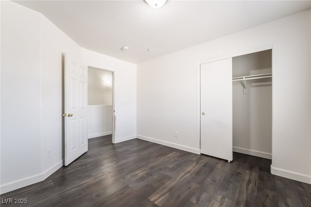 unfurnished bedroom featuring dark wood finished floors, a closet, and baseboards