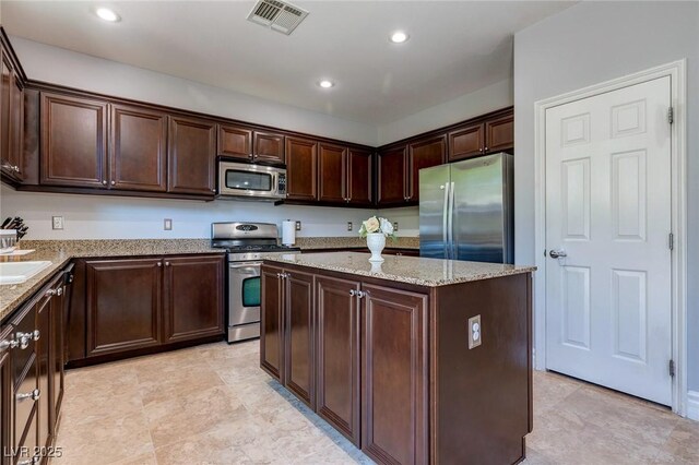 9780 Ziegler Ave, Las Vegas, NV 89148 - kitchen with appliances with stainless steel finishes, a kitchen island, dark brown cabinetry, light stone countertops, and recessed lighting