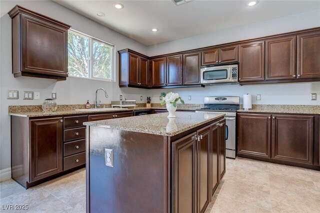 9780 Ziegler Ave, Las Vegas, NV 89148 - kitchen with stainless steel appliances, a sink, dark brown cabinets, light stone countertops, and a center island