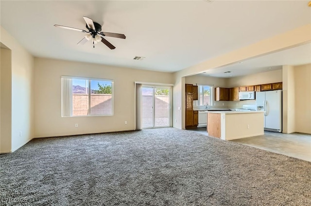 2728 Holmfault St, Henderson, NV 89044 - kitchen with white appliances, open floor plan, a kitchen island, light carpet, and a ceiling fan