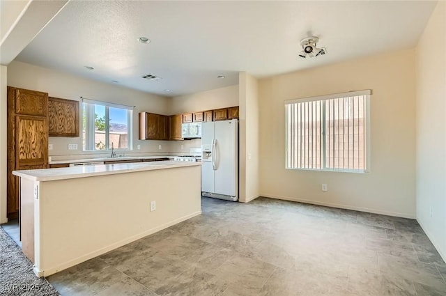 2728 Holmfault St, Henderson, NV 89044 - kitchen featuring white appliances, light countertops, a kitchen island, brown cabinets, and baseboards