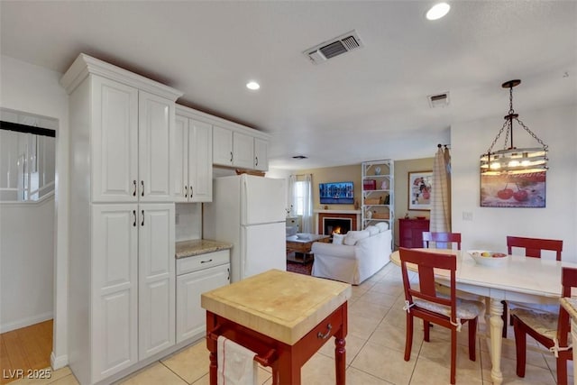 8388 Brad Oaks Cir, Las Vegas, NV 89123 - kitchen with freestanding refrigerator, a lit fireplace, white cabinets, recessed lighting, and decorative light fixtures