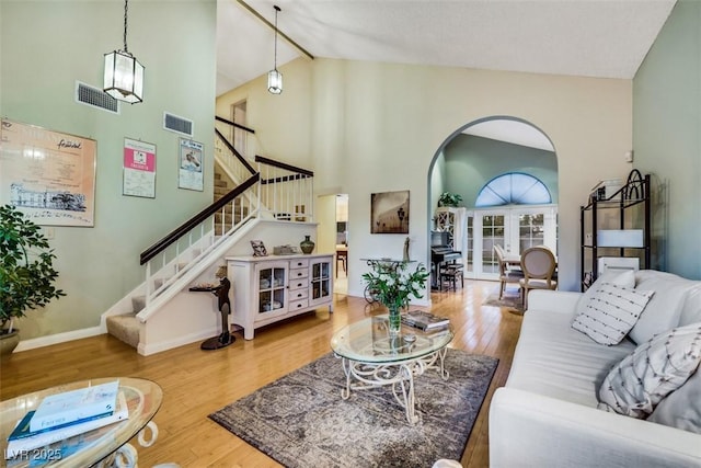 8388 Brad Oaks Cir, Las Vegas, NV 89123 - living area featuring high vaulted ceiling, arched walkways, wood finished floors, stairs, and baseboards
