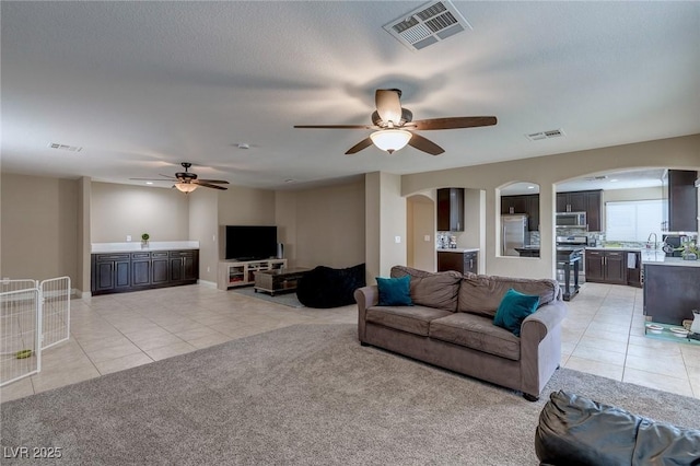 9469 Coral Shine Ct, Las Vegas, NV 89123 - living area with light tile patterned flooring, arched walkways, ceiling fan, and light carpet