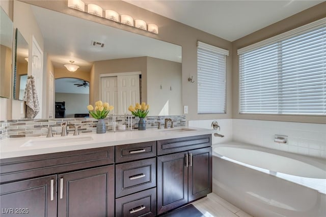 9469 Coral Shine Ct, Las Vegas, NV 89123 - bathroom featuring ceiling fan, a bath, double vanity, and tasteful backsplash