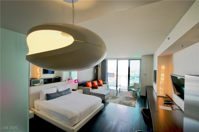 bedroom with a wall of windows and wood finished floors