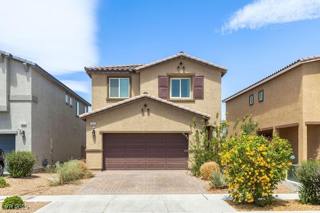 view of front of property with stucco siding, a tile roof, a garage, and decorative driveway