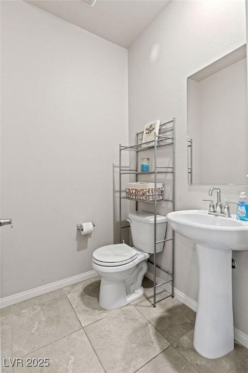 half bath with toilet, baseboards, and a sink