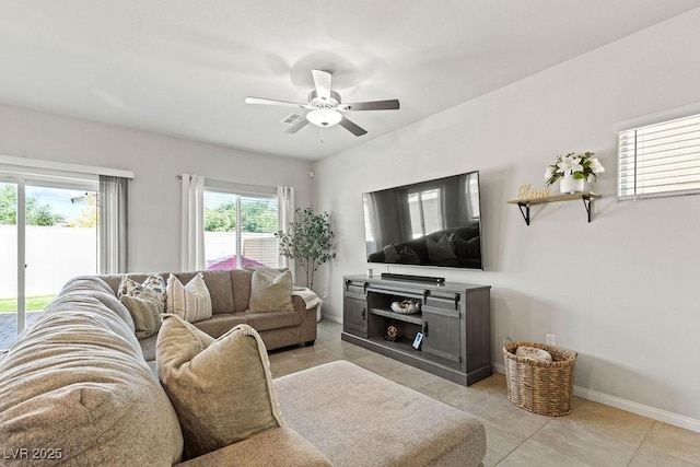 living area with ceiling fan, baseboards, and light tile patterned floors