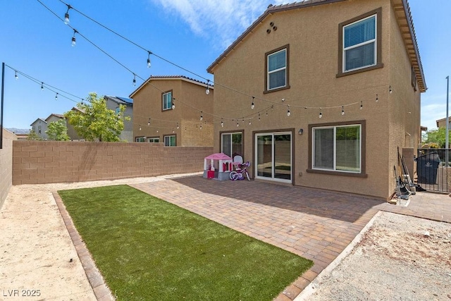 back of property with stucco siding and a patio
