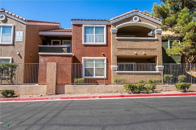 8101 W Flamingo Rd Unit 2006, Las Vegas, NV 89147 - view of front of home with stucco siding, a tiled roof, a balcony, and fence