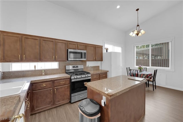 1893 Donnington Ct, Las Vegas, NV 89123 - kitchen featuring appliances with stainless steel finishes, light wood-style floors, a sink, high vaulted ceiling, and a chandelier