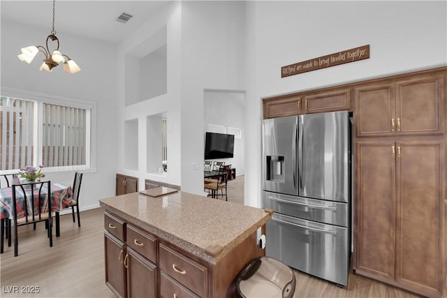 1893 Donnington Ct, Las Vegas, NV 89123 - kitchen with stainless steel refrigerator with ice dispenser, a high ceiling, a chandelier, a kitchen island, and light wood-style floors
