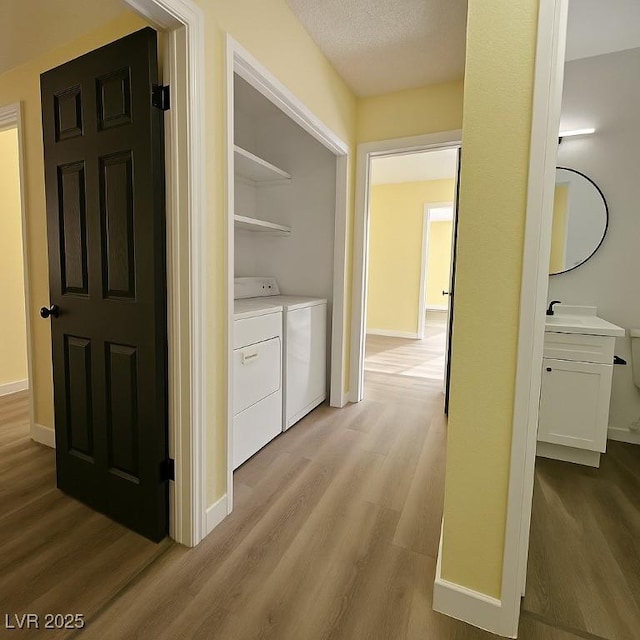 clothes washing area with light wood finished floors, independent washer and dryer, and baseboards