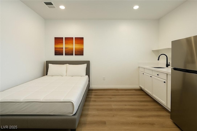 bedroom featuring freestanding refrigerator, a sink, recessed lighting, wood finished floors, and baseboards