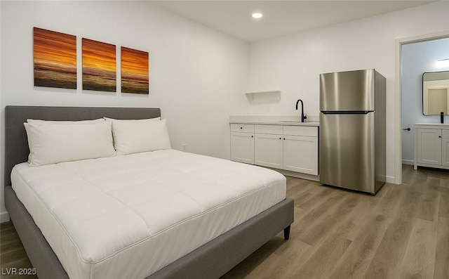 bedroom featuring freestanding refrigerator, light wood finished floors, recessed lighting, and a sink