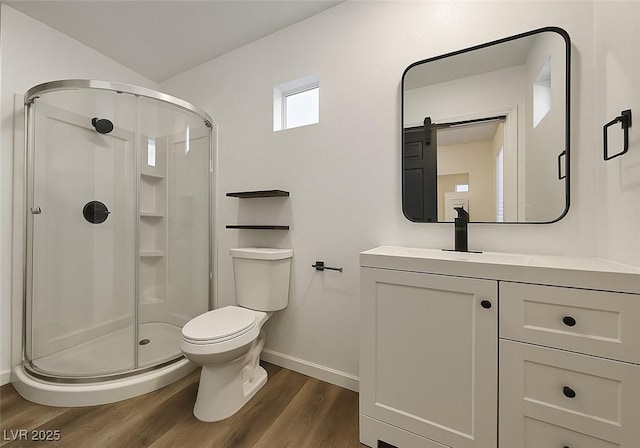 bathroom with baseboards, wood finished floors, a stall shower, toilet, and vanity