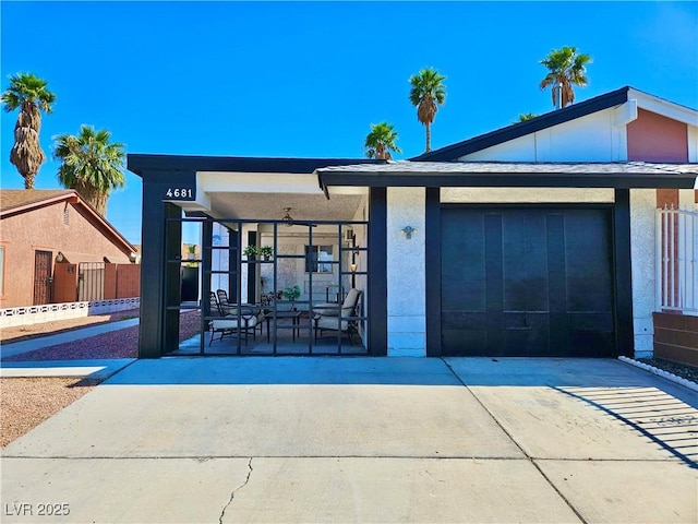 view of front of property with concrete driveway, a garage, fence, stucco siding, and a porch