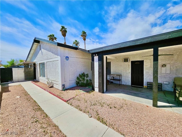 view of front of house featuring stucco siding, a porch, and a gate