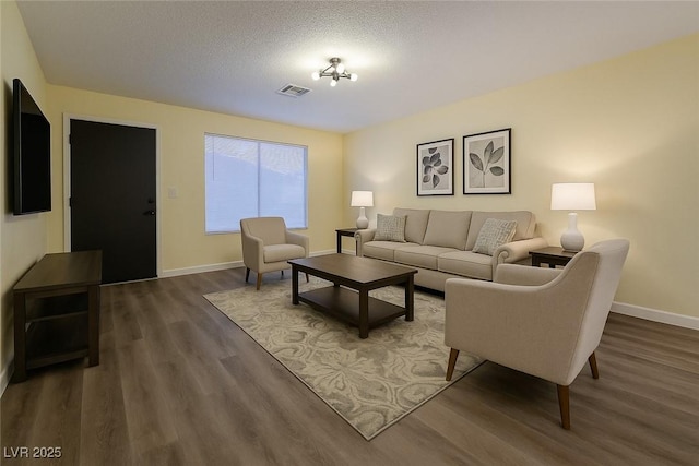 living area with wood finished floors, baseboards, and a textured ceiling