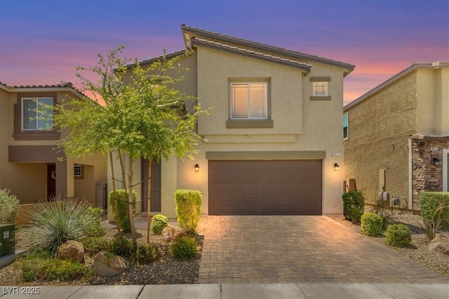 view of front of property featuring an attached garage, stucco siding, and decorative driveway