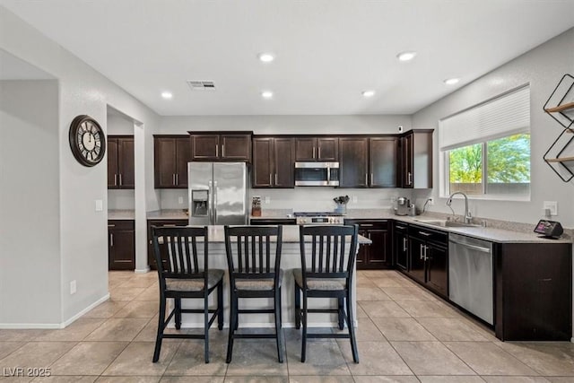 kitchen featuring stainless steel appliances, a sink, light tile patterned floors, a breakfast bar area, and recessed lighting