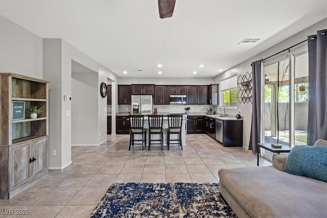 kitchen featuring stainless steel appliances, open floor plan, a sink, light tile patterned flooring, and light countertops