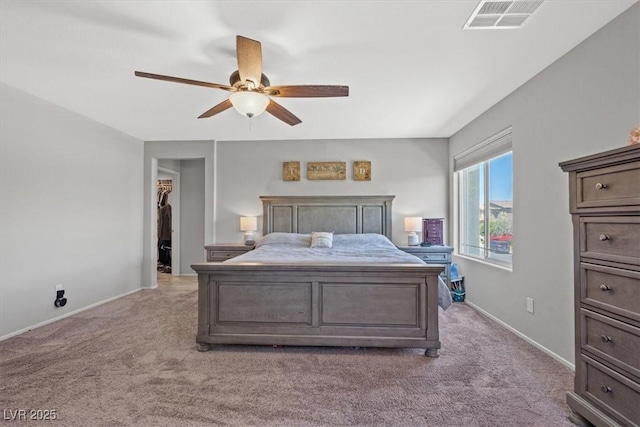 bedroom with light carpet, baseboards, a ceiling fan, and a spacious closet