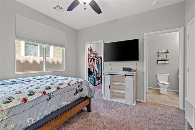 bedroom with a walk in closet, a closet, light colored carpet, connected bathroom, and baseboards