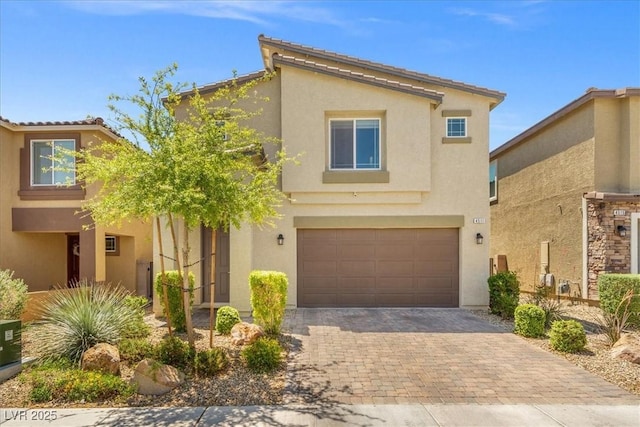 view of front of house with an attached garage, stucco siding, and decorative driveway
