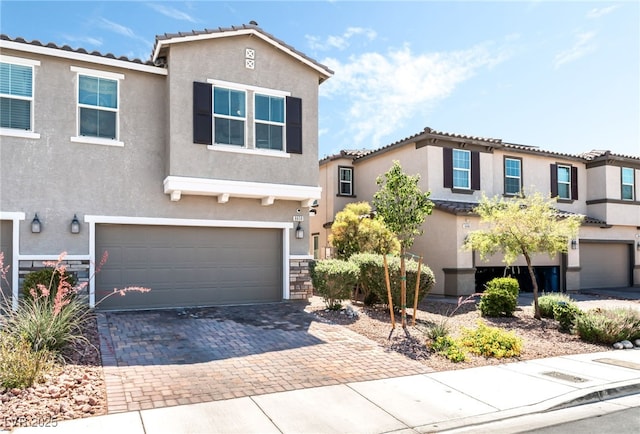 view of front of property with stucco siding, a garage, decorative driveway, and a tile roof