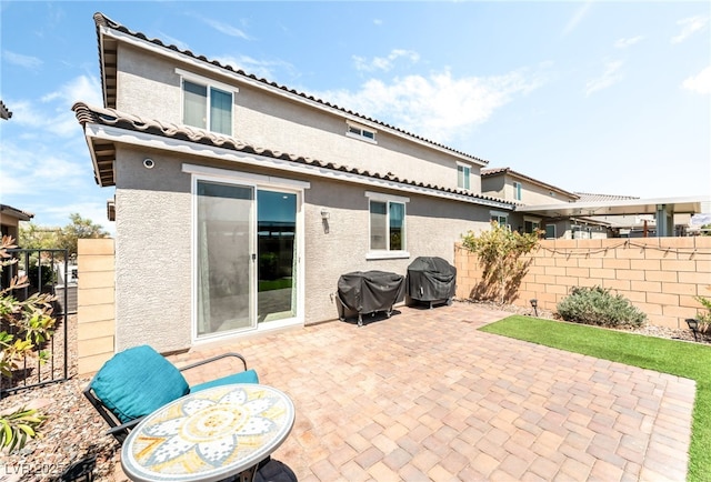 rear view of property featuring stucco siding, a patio, fence, and a tile roof