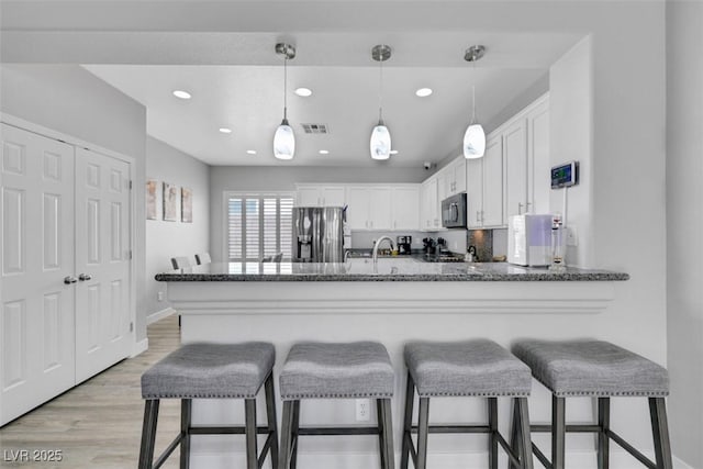 8836 Martin Downs Pl, Las Vegas, NV 89131 - kitchen featuring stainless steel fridge, black microwave, a peninsula, white cabinetry, and recessed lighting