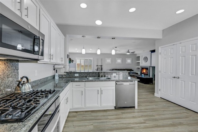 8836 Martin Downs Pl, Las Vegas, NV 89131 - kitchen featuring stainless steel appliances, a sink, open floor plan, a peninsula, and white cabinets