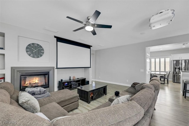 8836 Martin Downs Pl, Las Vegas, NV 89131 - cinema room featuring ceiling fan, a glass covered fireplace, light wood-style flooring, and baseboards