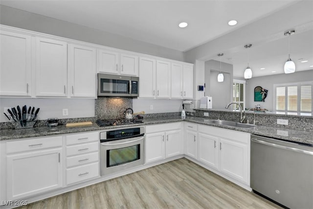 8836 Martin Downs Pl, Las Vegas, NV 89131 - kitchen with stainless steel appliances, a sink, white cabinetry, dark stone countertops, and recessed lighting