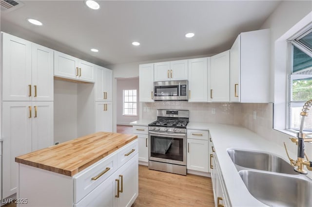 2107 Fountain Springs Dr, Henderson, NV 89074 - kitchen with appliances with stainless steel finishes, a sink, wood counters, white cabinetry, and tasteful backsplash