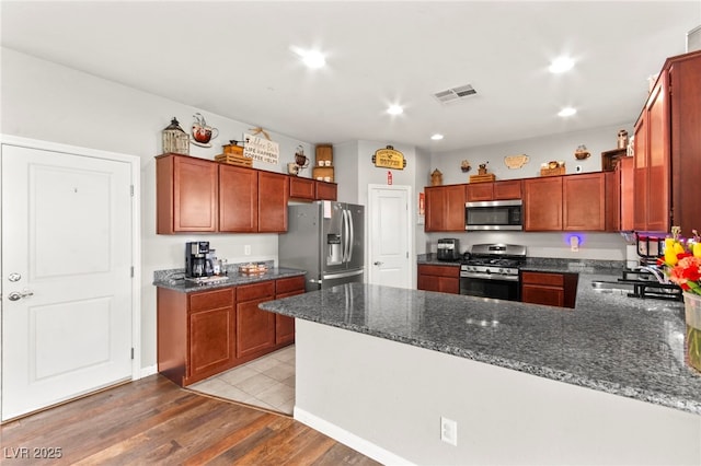 2672 Painted Mist Ct, Las Vegas, NV 89142 - kitchen with stainless steel appliances, light wood finished floors, a peninsula, recessed lighting, and dark stone counters