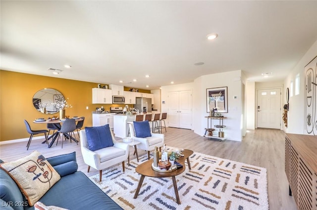 living room with light wood-style floors, recessed lighting, and baseboards