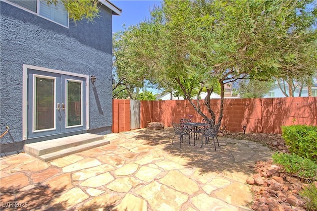 view of patio with french doors, fence, and outdoor dining space