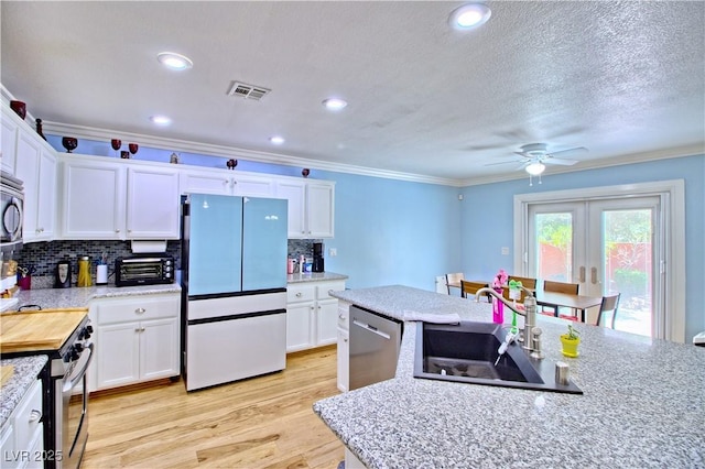 kitchen with stainless steel appliances, a sink, ornamental molding, a ceiling fan, and white cabinetry