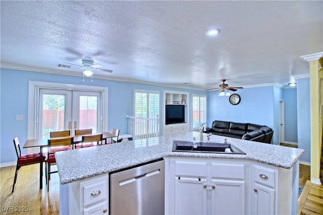 kitchen featuring ceiling fan, dishwasher, a sink, open floor plan, and a textured ceiling