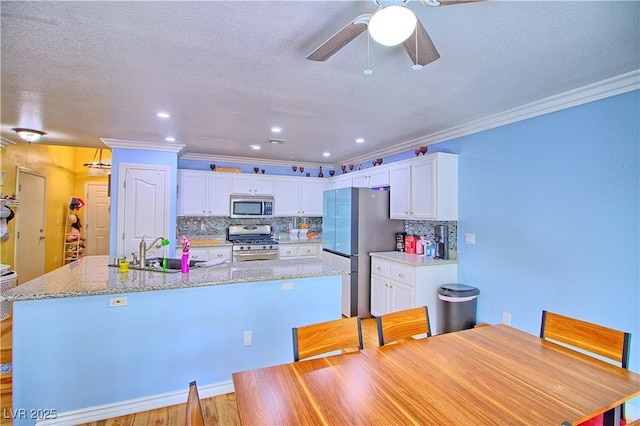7728 Whispering River St, Las Vegas, NV 89131 - kitchen with stainless steel appliances, a sink, ornamental molding, a center island with sink, and ceiling fan