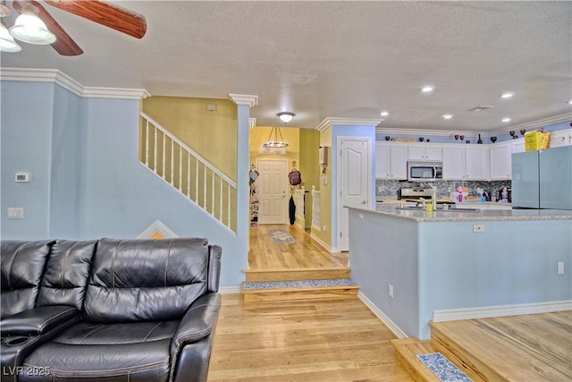kitchen with stainless steel microwave, light wood-type flooring, freestanding refrigerator, white cabinets, and ceiling fan