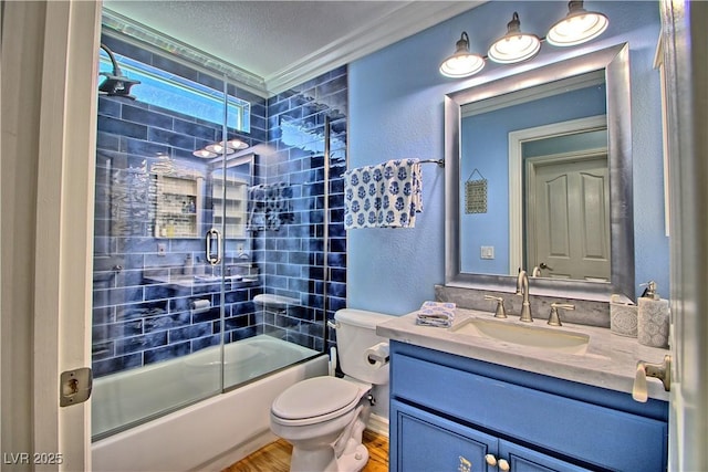 full bath with a textured wall, vanity, wood finished floors, toilet, and shower / bath combination with glass door