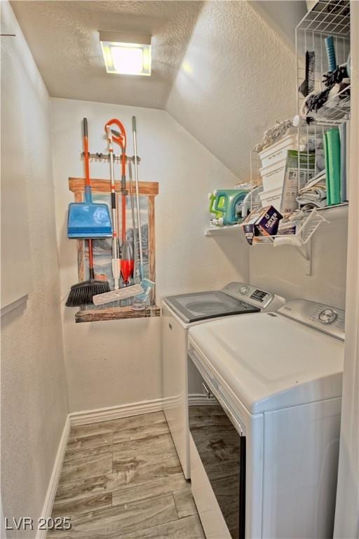 laundry room with washer and clothes dryer, light wood-style flooring, a textured ceiling, and baseboards