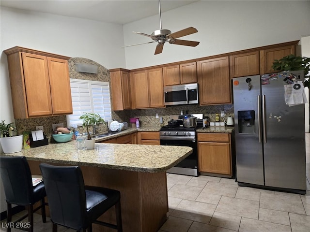 6361 Copperfield Ave, Las Vegas, NV 89108 - kitchen with stainless steel appliances, a peninsula, decorative backsplash, ceiling fan, and high vaulted ceiling