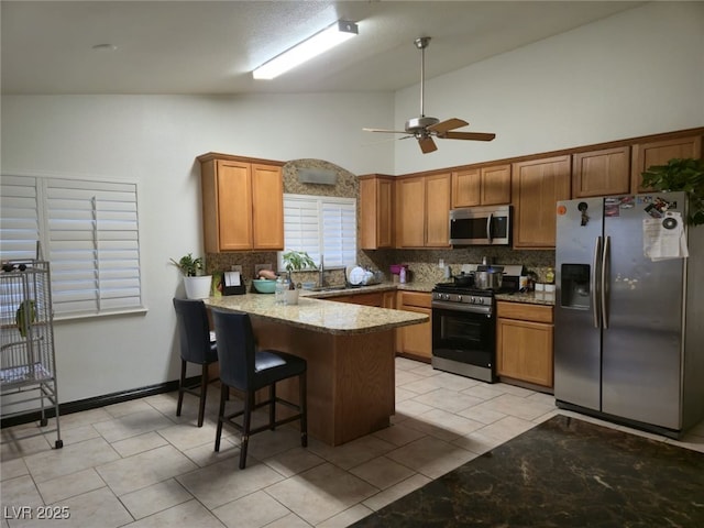 6361 Copperfield Ave, Las Vegas, NV 89108 - kitchen with stainless steel appliances, backsplash, a peninsula, a ceiling fan, and brown cabinets
